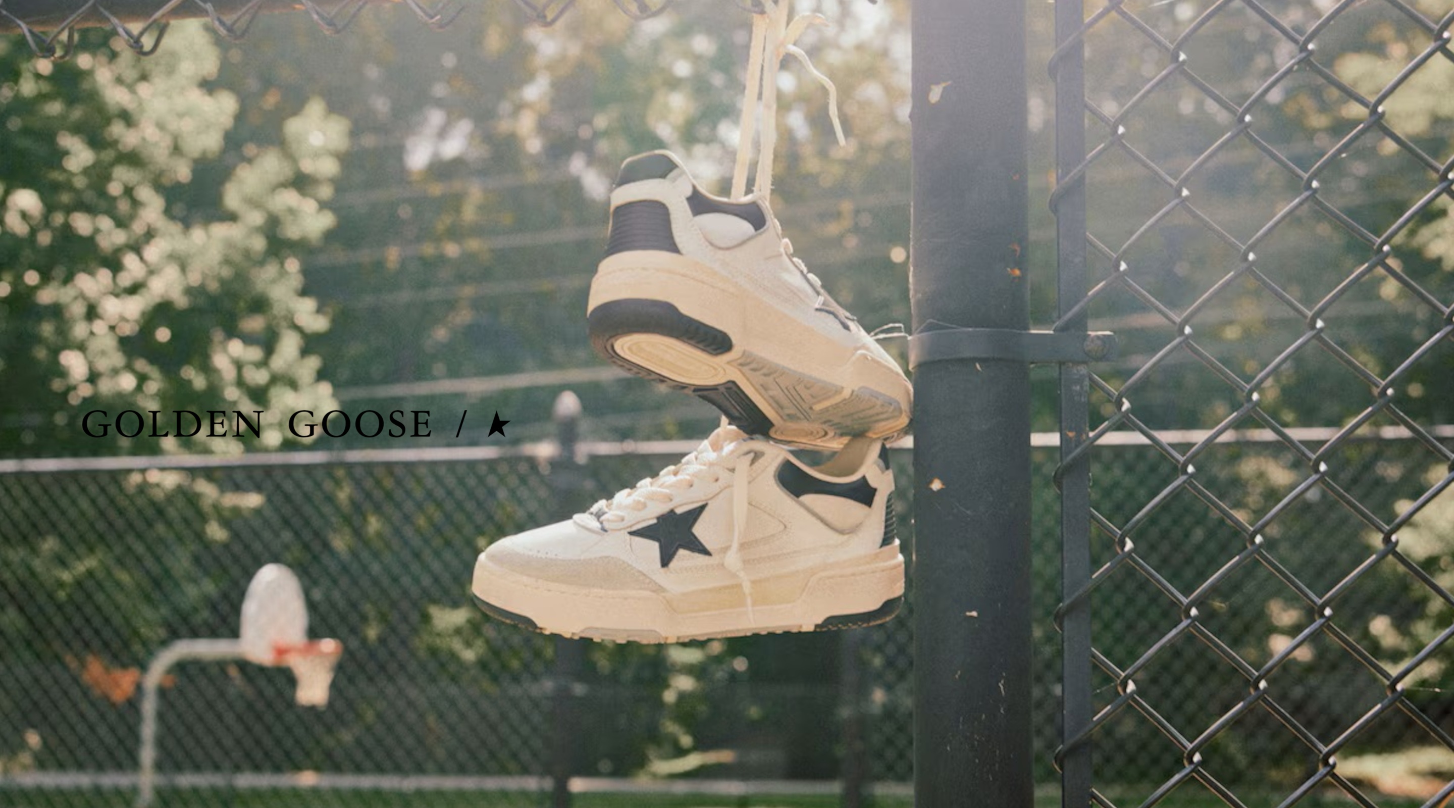 aufgehängte golden goose sneaker an einem zaun auf einem basketballfeld